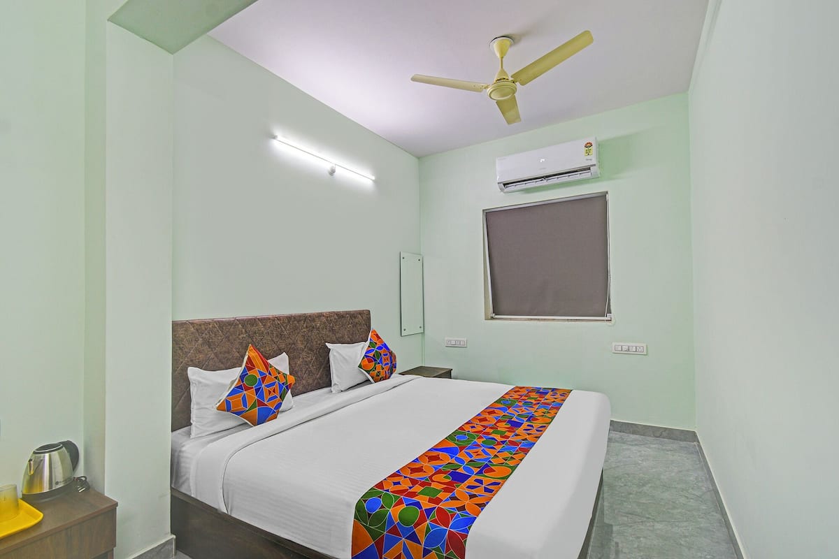 Ein Hotelzimmer mit Bett, Deckenventilator, Klimaanlage und einem Fenster mit Jalousie.