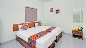 A double bed with a colorful geometric bedspread, a wooden headboard, and two pillows. - Fabhotel Legacy (Hyderabad)