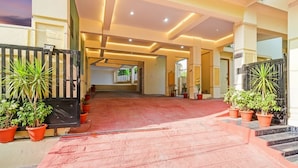 A hotel entrance with a red carpet, potted plants, and a black gate. - Fabhotel Legacy (Hyderabad)