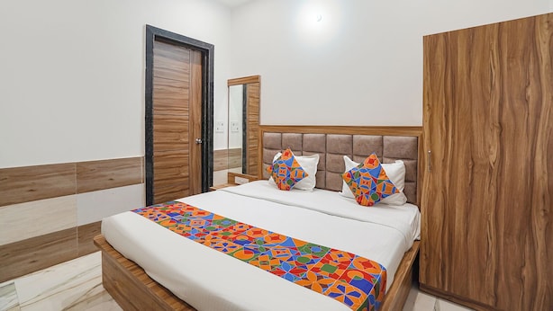 A bedroom with a bed, wooden wardrobe, and a door. - Fabhotel Devi Heritage (Vrindavan)
