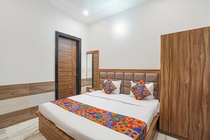 A bedroom with a bed, wooden wardrobe, and a door. - Fabhotel Devi Heritage (Vrindavan)