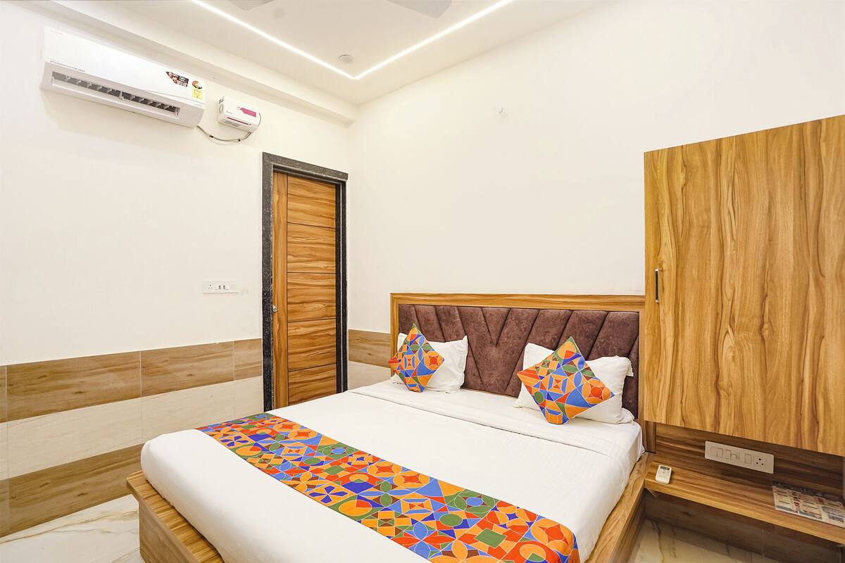 A hotel room with a bed, a wardrobe, and an air conditioning unit on the wall.