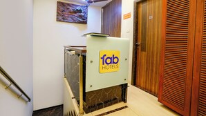 A hotel reception area with a marble counter, a ceiling fan, and a wooden door. - Fabhotel Amfahh Inn (Mumbai)