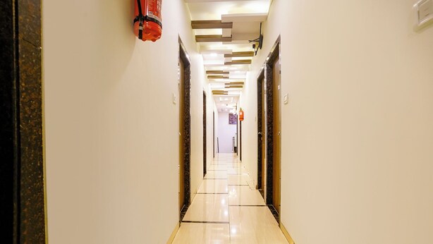 A hotel hallway with a modern design, featuring a marble floor and a fire extinguisher mounted on the wall. - Fabhotel Amfahh Inn (Mumbai)