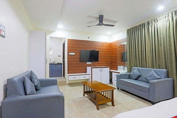 A living room with a sofa, a coffee table, a TV mounted on the wall, and a curtain.
