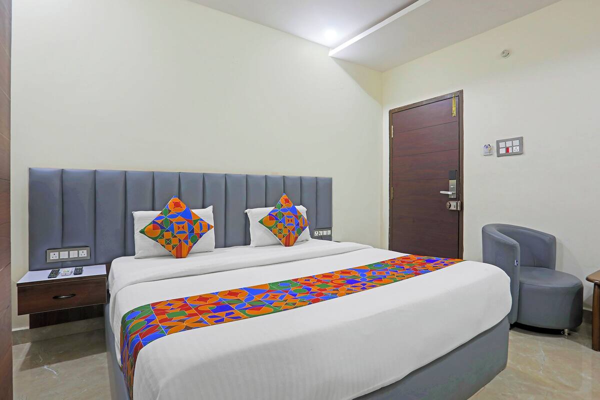 A hotel room with a bed, a nightstand, a chair, and a door.