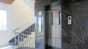 A modern elevator with a digital display, a marble wall, and a glass staircase. - Fabhotel Rr Residency I (Khammam)