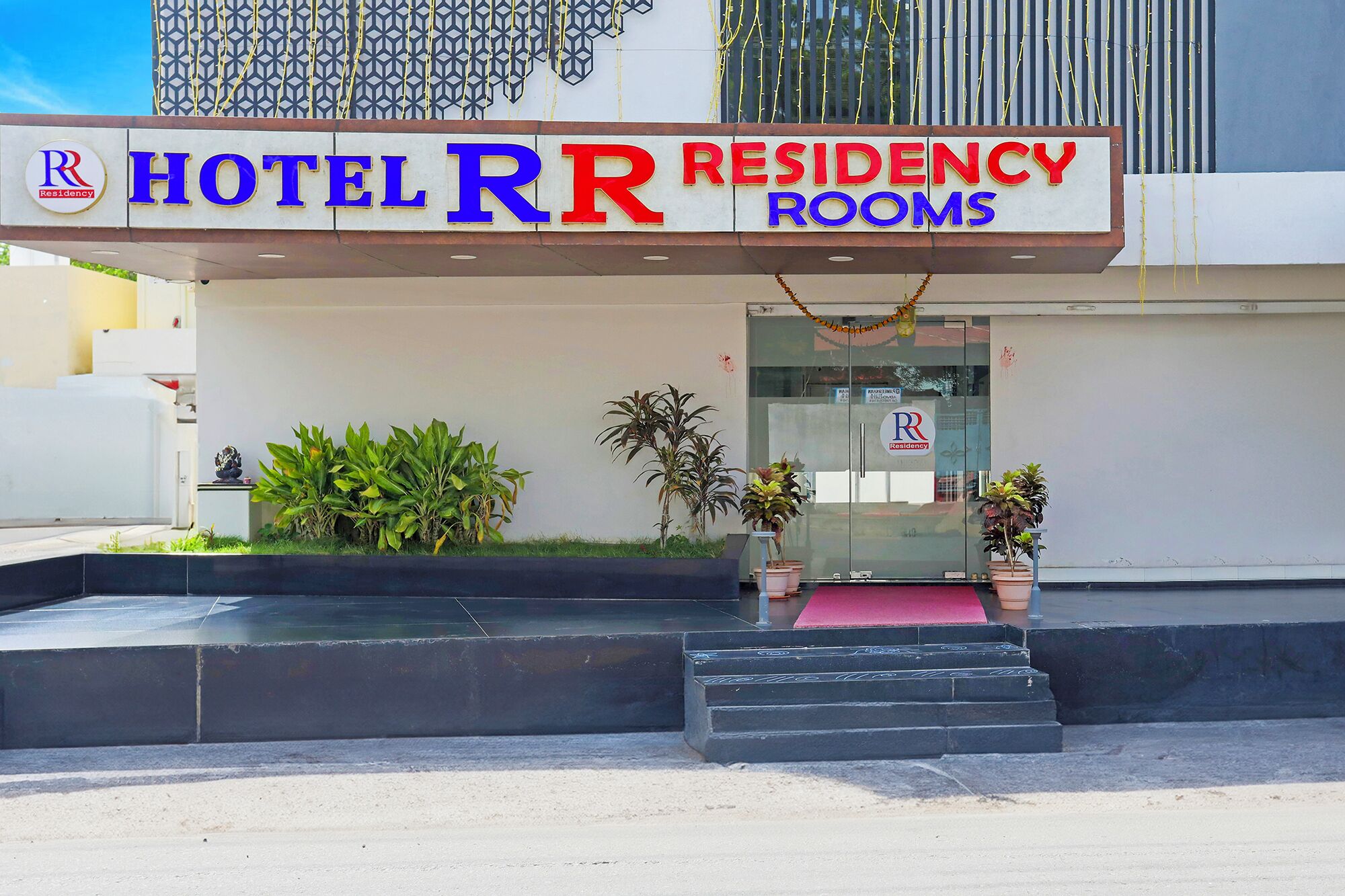 Entrada de un hotel con un letrero que dice "HOTEL RR RESIDENCY ROOMS".