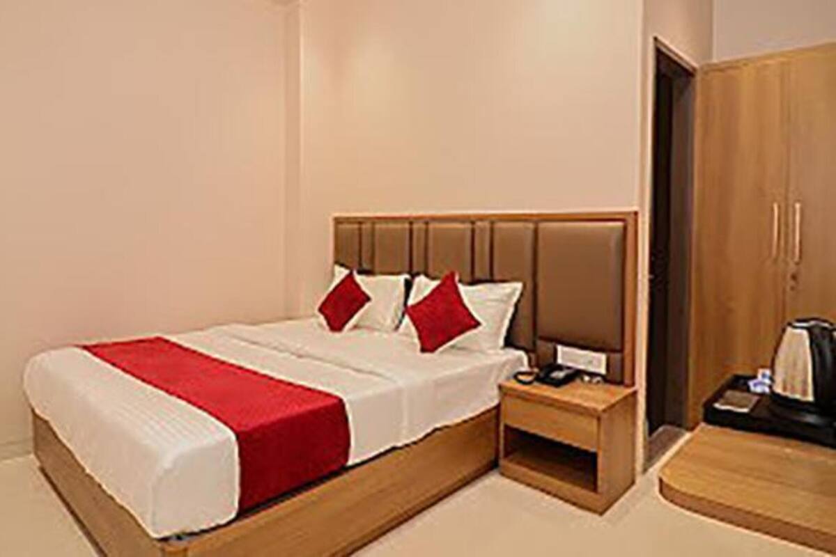 A hotel room with a bed, a bedside table, and a wardrobe.