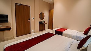 A hotel room with two beds, a TV, a wooden door, and a small table with a mirror. - FabExpress Ascent Star Inn (Mumbai)