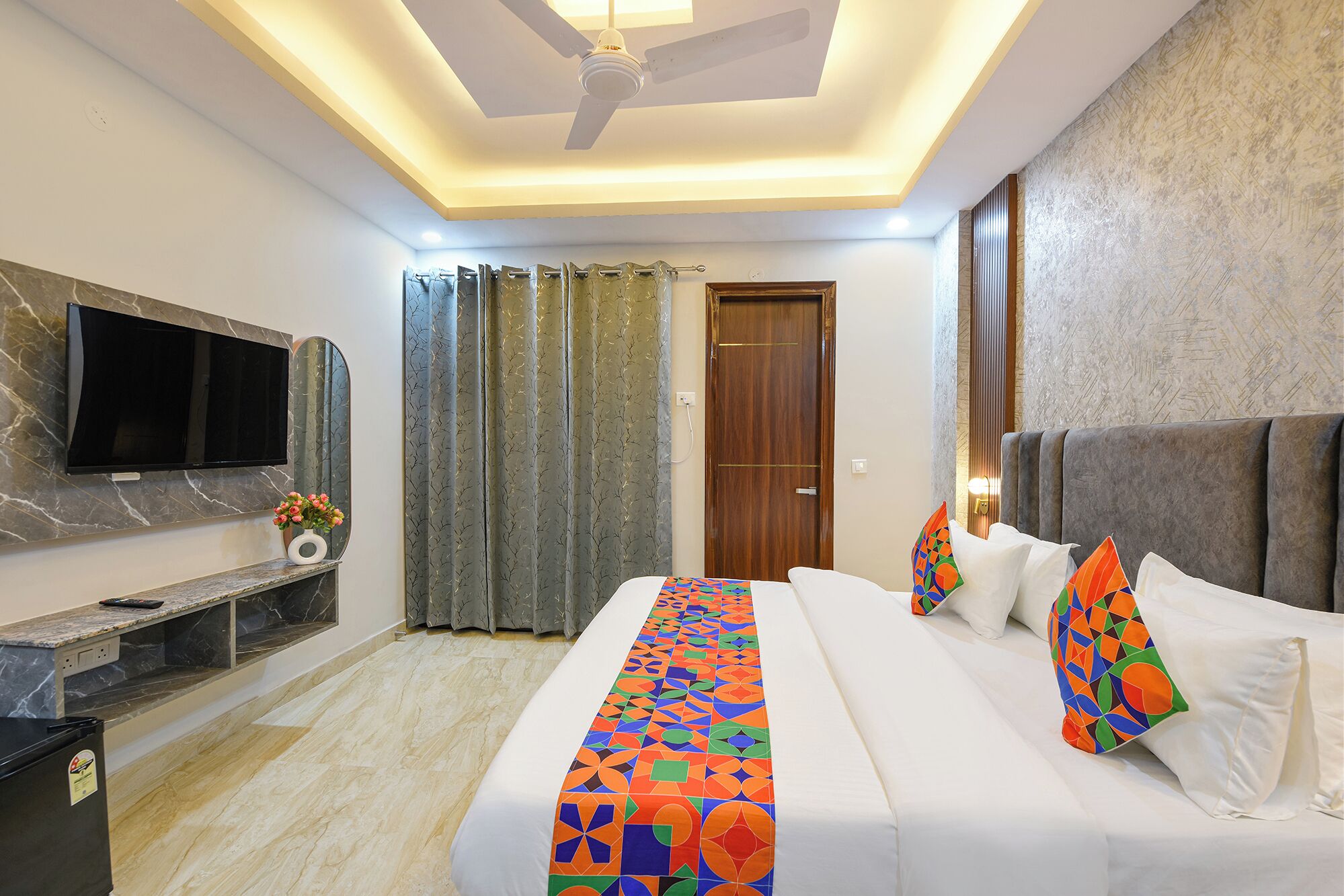 A hotel room with a bed, a TV, a desk, and a shower area.