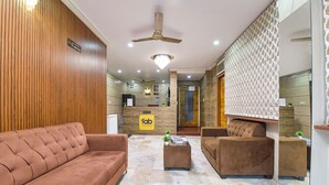 A hotel reception area with a reception desk, a brown sofa, a coffee table, and a patterned wall. - Fabhotel Silver Stay 04 (Jaipur)
