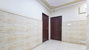 A hallway with two doors, each with a sign above them. The walls are textured, and the floor is tiled. - Fabhotel Silver Stay 04 (Jaipur)