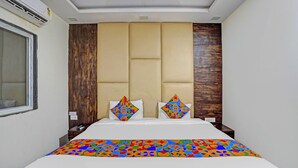 Una habitación de hotel con una cama grande, cabecera de madera y colcha de diseño geométrico y colores vivos.