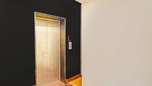 Un ascensor con un panel de control, una pared negra y un piso de baldosas.