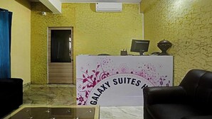 A reception area with a Galaxy Suites sign, a reception desk, a computer, and a black leather chair. - FabHotel Galaxy Suites - Near MP Layout Metro Station, Hebbal (Bengaluru)