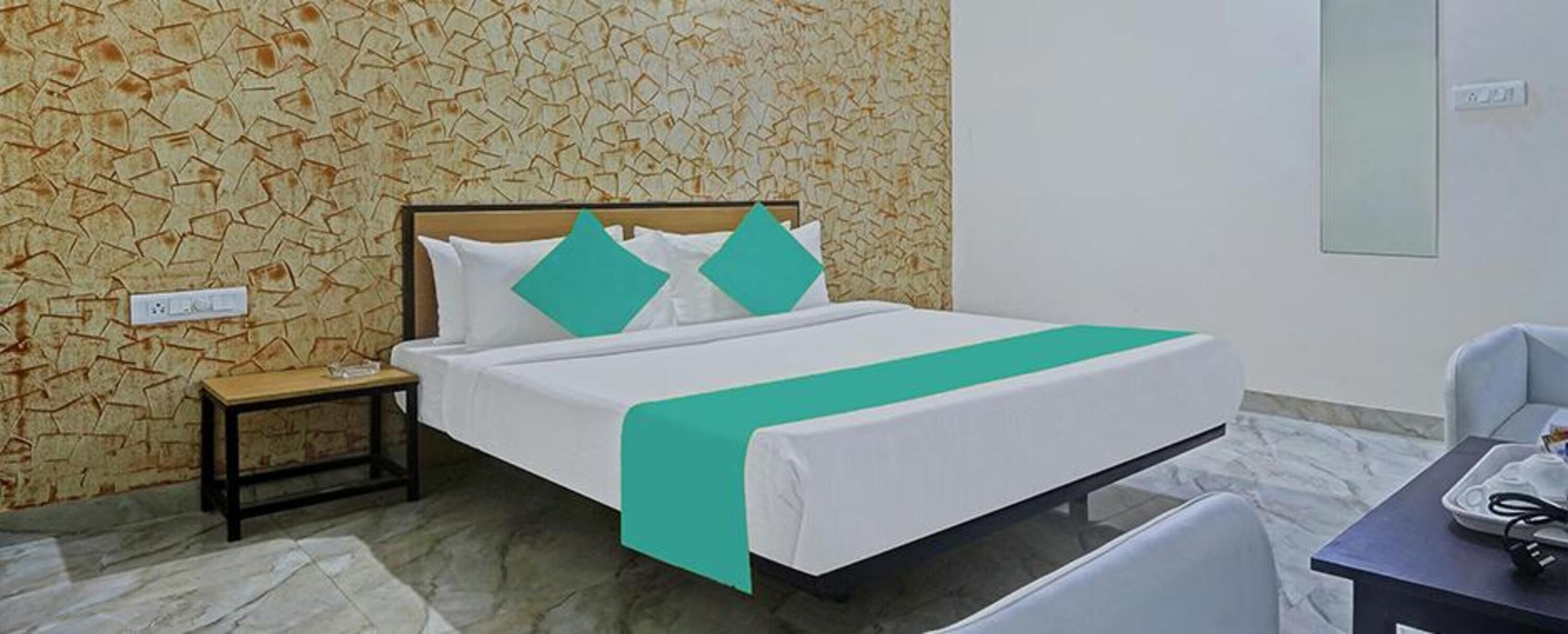 Habitació d'hotel amb un llit, una tauleta de nit, una cadira i un escriptori.