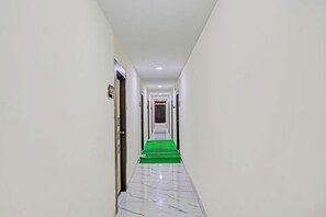 A narrow, well-lit hallway with a green carpet leading to a door marked with the number 202. - Fabhotel Sunrise (Hanmakonda)