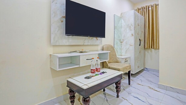 Una sala de estar con un televisor de pantalla plana montado en la pared, un sofá, una mesa de centro con botellas y un armario.