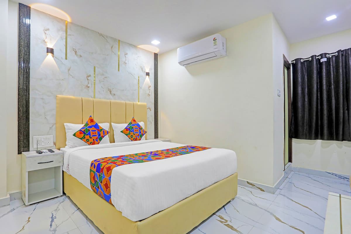 Una habitación de hotel con cama, mesita de noche y aire acondicionado instalado en la pared.