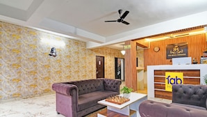 A hotel lobby with a purple sofa, a chessboard, and a reception desk with a sign reading "fab hotel". - Fabhotel 85 The Seven Wonders (Barasat)