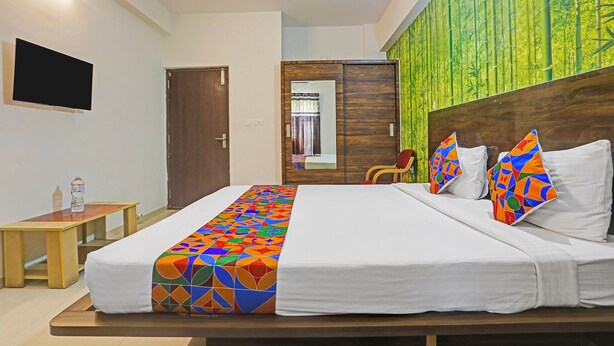 Habitación de hotel con cama, cabecero de madera, espejo, armario y papel tapiz de bambú verde.