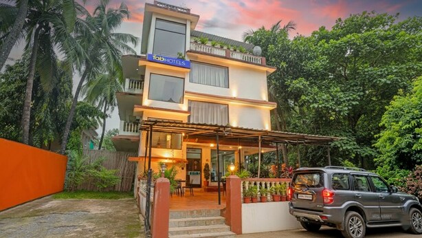 A modern hotel with a two-story structure, a covered outdoor seating area, and a car parked in front. - Fabhotel Balaji Resort (Calangute)
