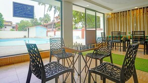 A dining area with a chessboard, chairs, and a view of a swimming pool. - Fabhotel Balaji Resort (Calangute)