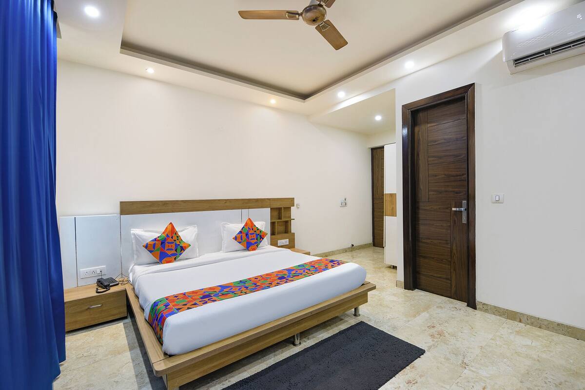 A bedroom with a bed, a wooden headboard, a ceiling fan, an air conditioning unit, and a door.
