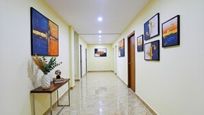 A hallway with a marble floor, a console table with a vase and a book, and several framed artworks on the walls. - FabHotel Sujatha Residency - Near Channasandra Railway Station (Bengaluru)