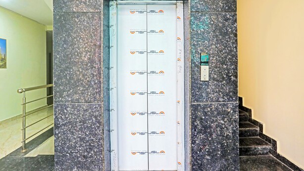 A staircase with a handrail, a wall with a textured surface, and a door with a logo. - FabHotel Sujatha Residency - Near Channasandra Railway Station (Bengaluru)