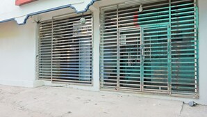 A building with two large metal shutters, a red awning, and a concrete ground. - FabHotel Sujatha Residency - Near Channasandra Railway Station (Bengaluru)