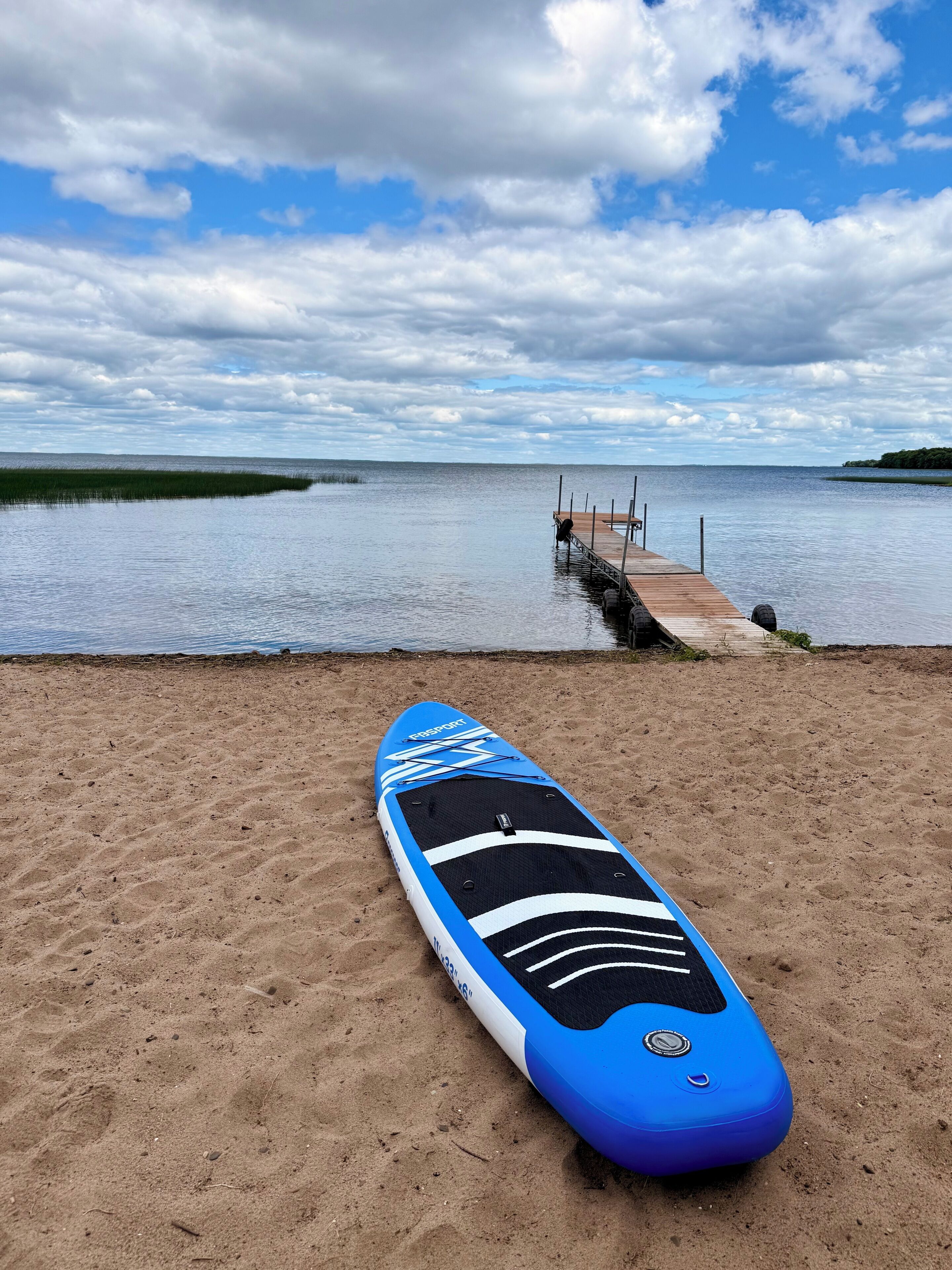 Una spiaggia con una tavola da paddleboard blu poggiata sulla sabbia.