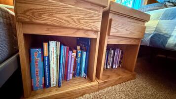 A wooden bookshelf with books, a lamp, and a bed in the background.