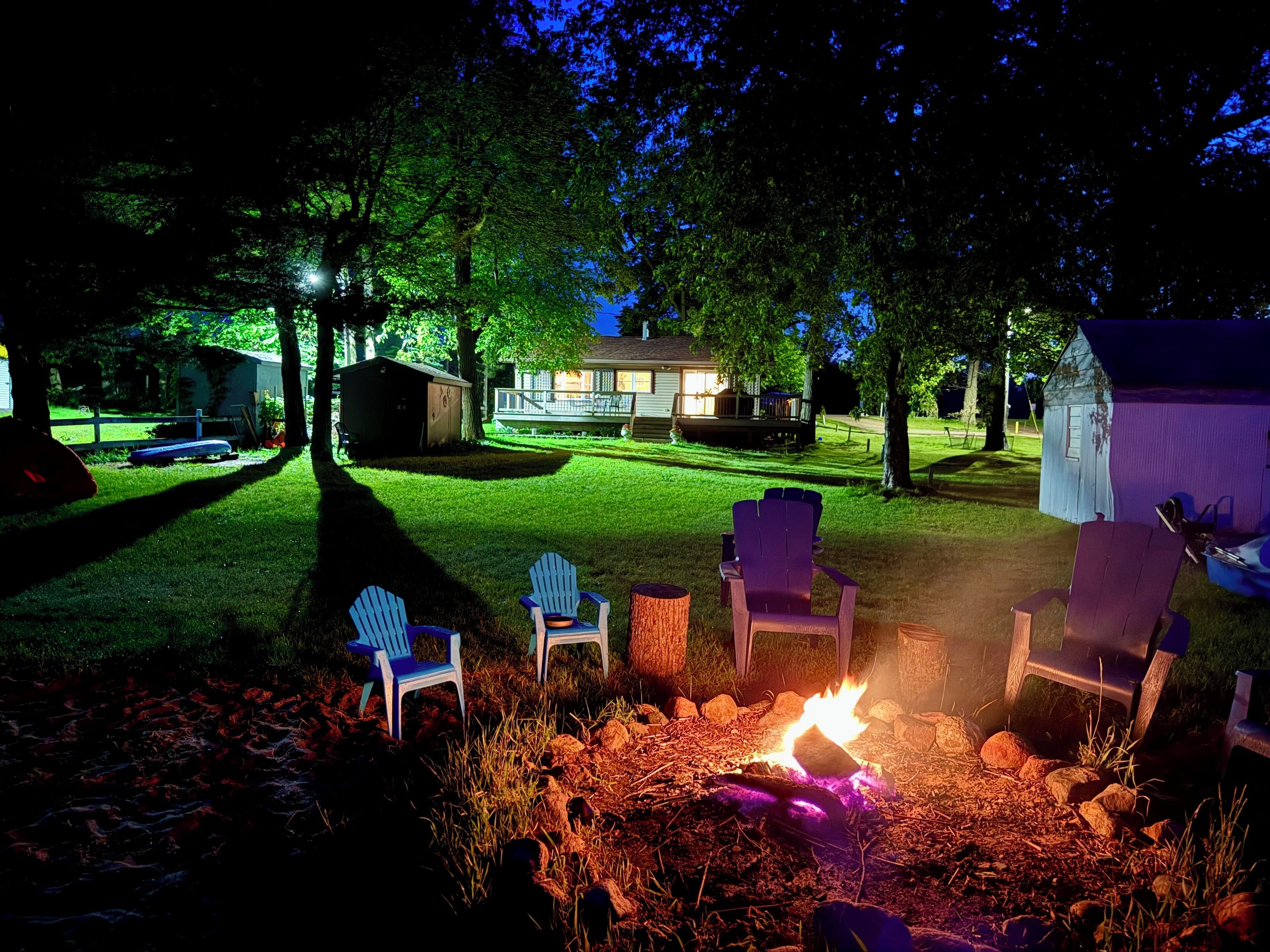 A backyard with a fire pit, outdoor seating, and a house in the background.