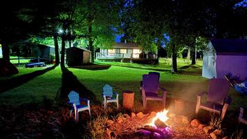 A backyard with a fire pit, outdoor seating, and a house in the background.