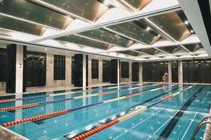 A large indoor swimming pool with multiple lanes, a lifeguard chair, and a ladder. - MOONRISE HOTELS & RESORTS (Deyang)