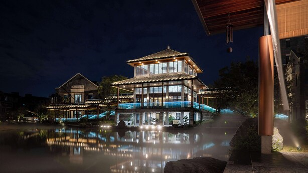 A multi-story building with a traditional architectural style, featuring large windows and a reflective pool in front. - MOONRISE HOTELS & RESORTS (Deyang)