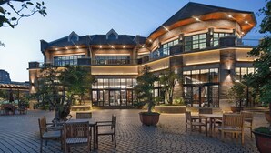 A multi-story building with a brick facade, large windows, and outdoor seating area with tables and chairs. - MOONRISE HOTELS & RESORTS (Deyang)