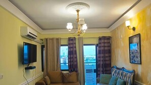 Una sala de estar con sofá, sillón, televisor y una araña.