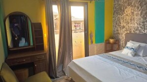 Habitación de hotel con cama, una silla, cómoda y ventana con cortinas.