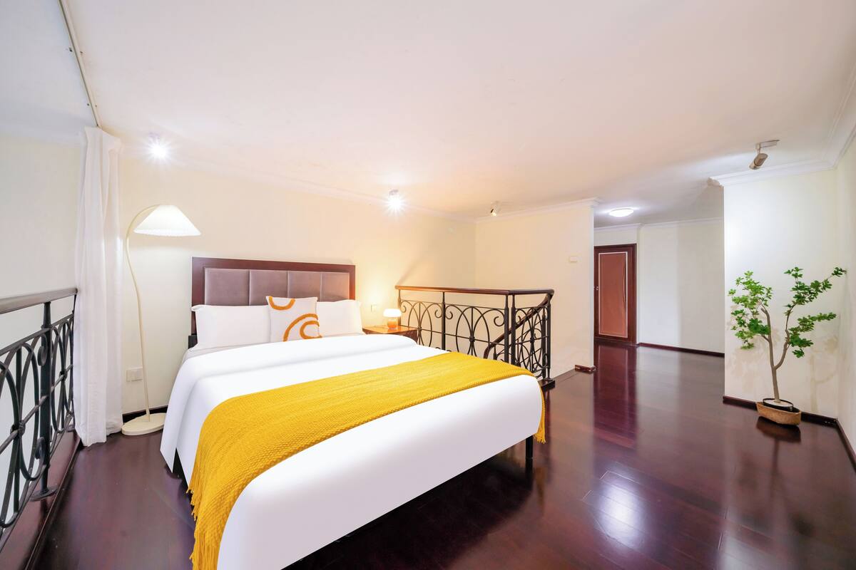 A hotel room with a bed, bedside lamp, and a potted plant.
