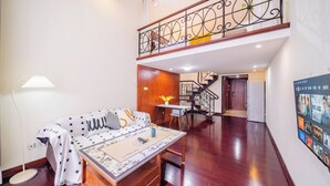 A spacious living area with a sofa, a coffee table, and a staircase leading to an upper floor. - Guangzhou Duoya Intl. Service Apartment (Guangzhou)