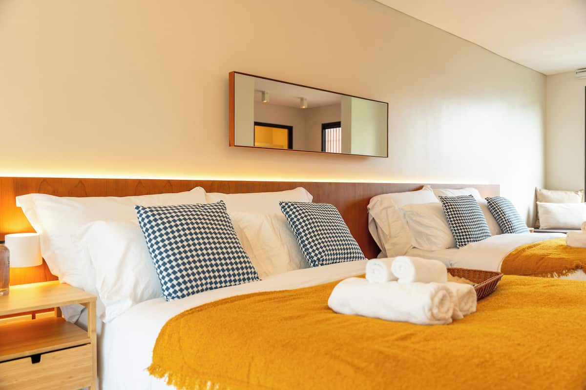Une chambre d’hôtel avec un grand lit, plusieurs oreillers, une table de chevet avec une lampe et un miroir au mur.