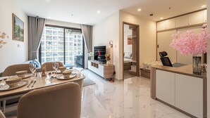A modern living room with a dining area, a TV, and a small kitchen. - LA Nest - Vena Nest (Ho Chi Minh City)