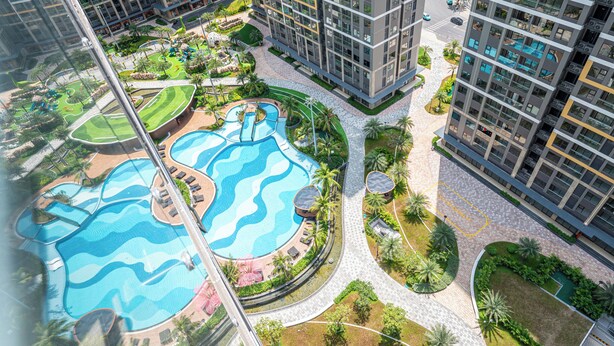 A high-rise residential building with a rooftop pool area, landscaped gardens, and a pedestrian walkway. - LA Nest - Vena Nest (Ho Chi Minh City)
