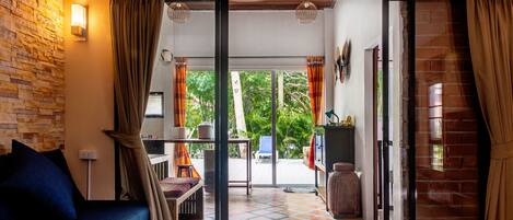 A cozy living area with a sofa, a dining table, and a kitchen area visible through an open sliding door.