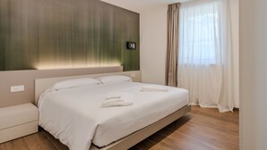 Et moderne hotelværelse med en stor seng, et natbord og et panel monteret på væggen.