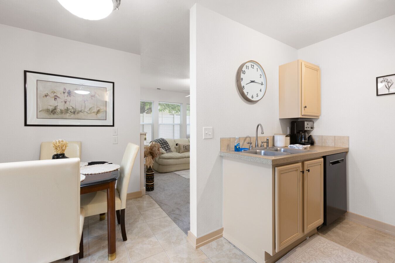 A modern kitchen with a built-in dishwasher, a clock, and a coffee maker.