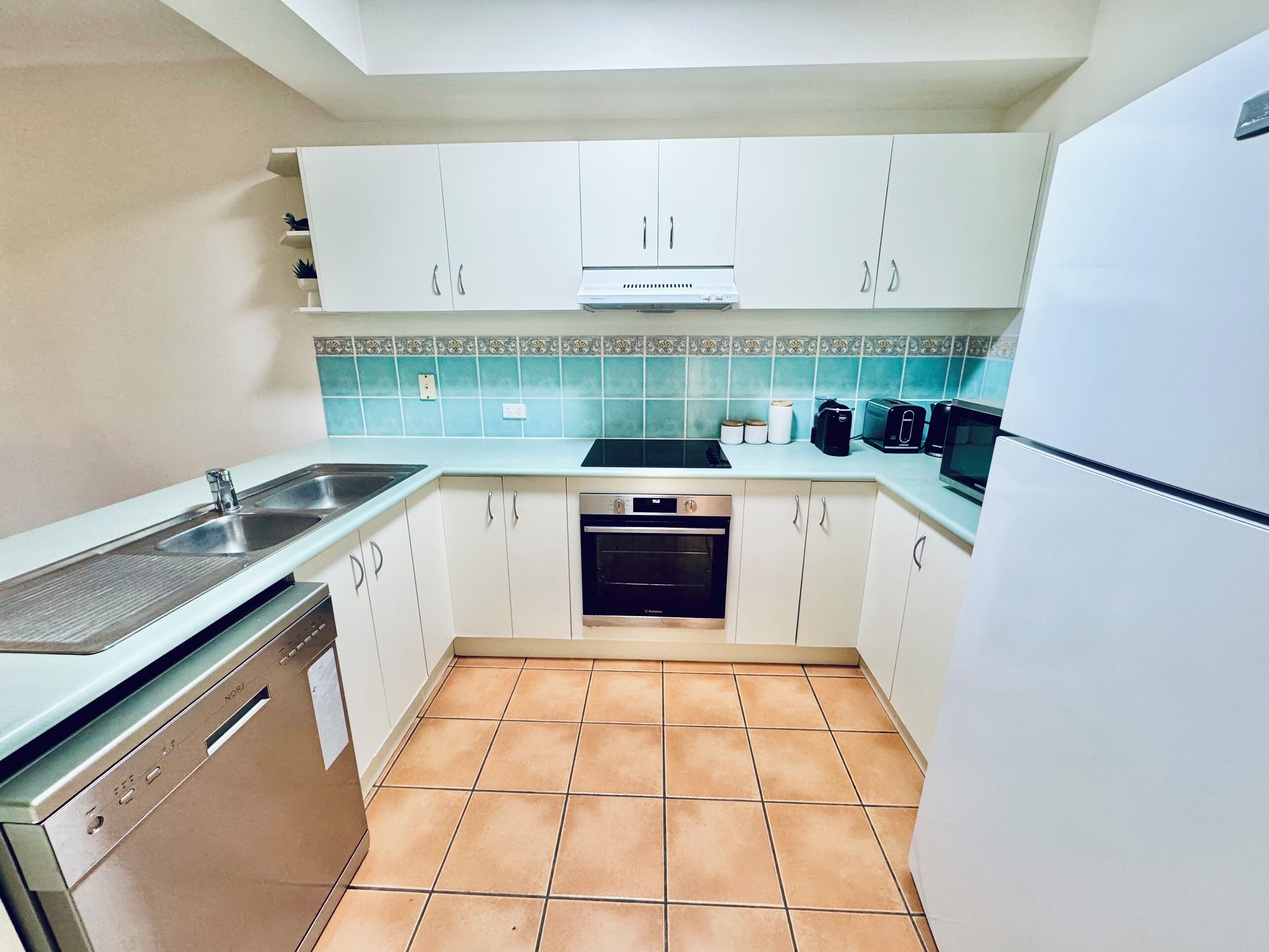A compact kitchen with white cabinets, a dishwasher, a stove, and a microwave.